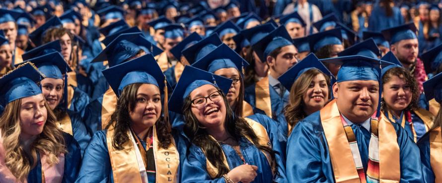 Graduates smile while wearing blue caps and gowns.