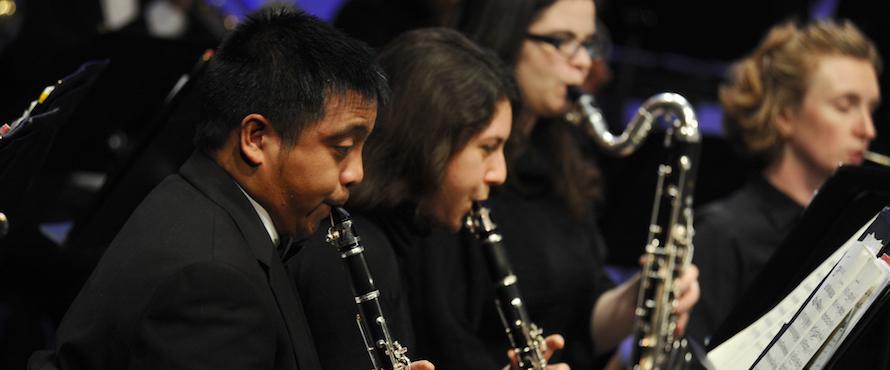 Four members of the Wind Ensemble play their instruments on stage.