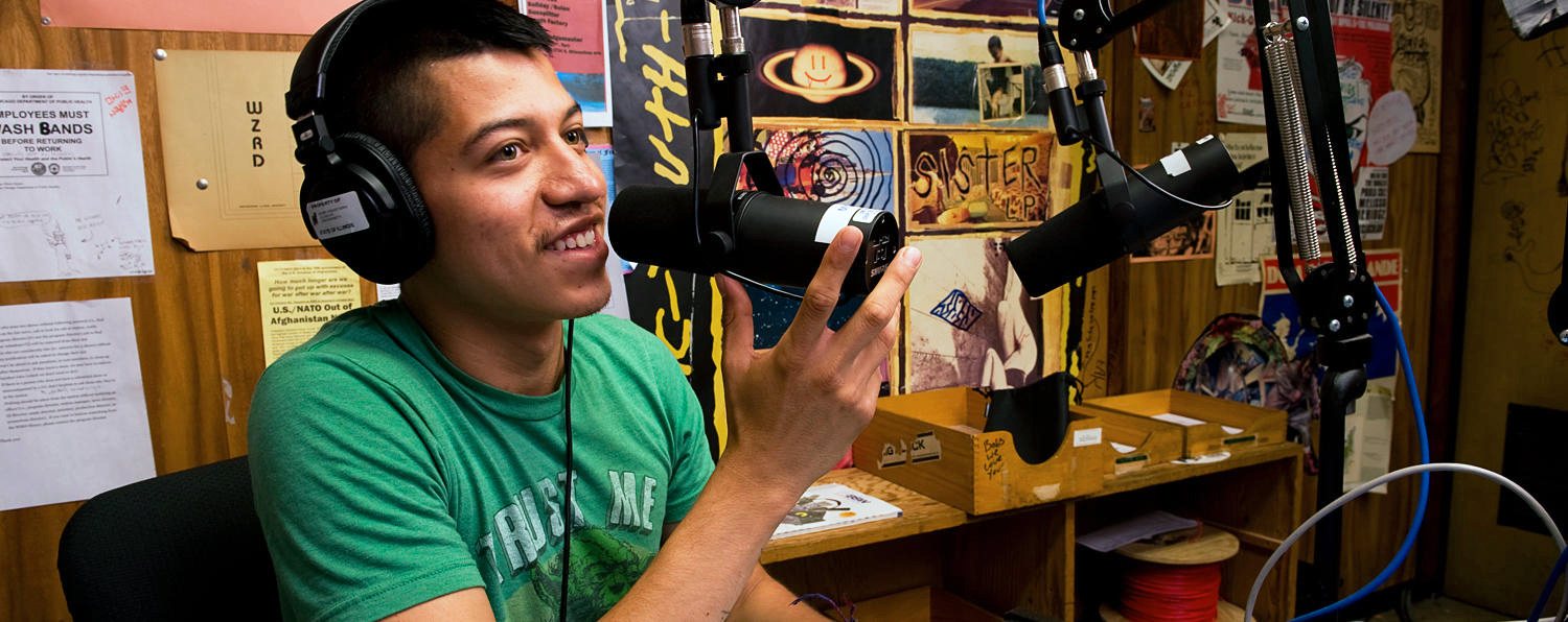 Northeastern Illinois University smiling student performing vibrant conversations in a microphone.