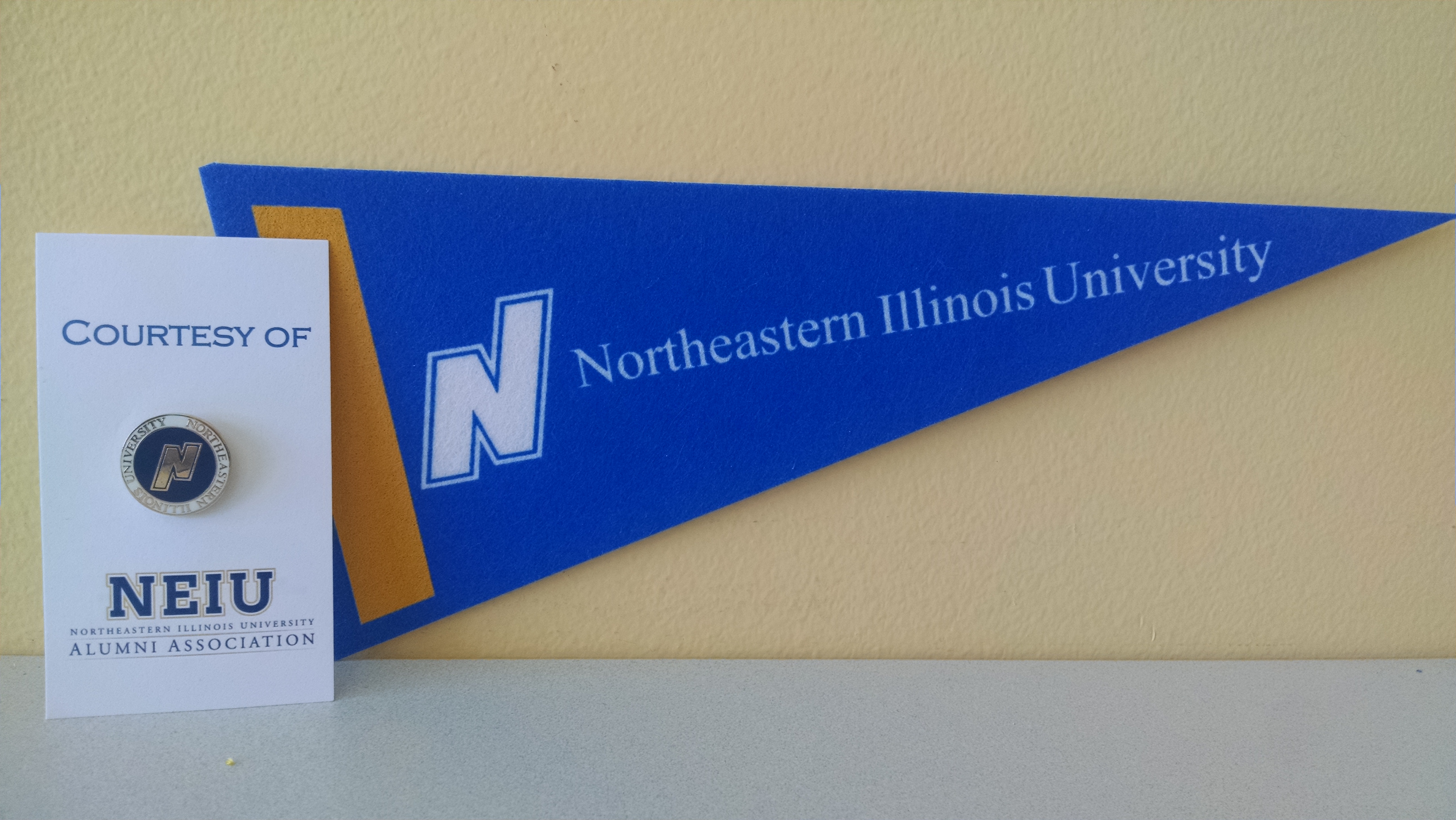 A blue Northeastern pennant hangs on a yellow wall.